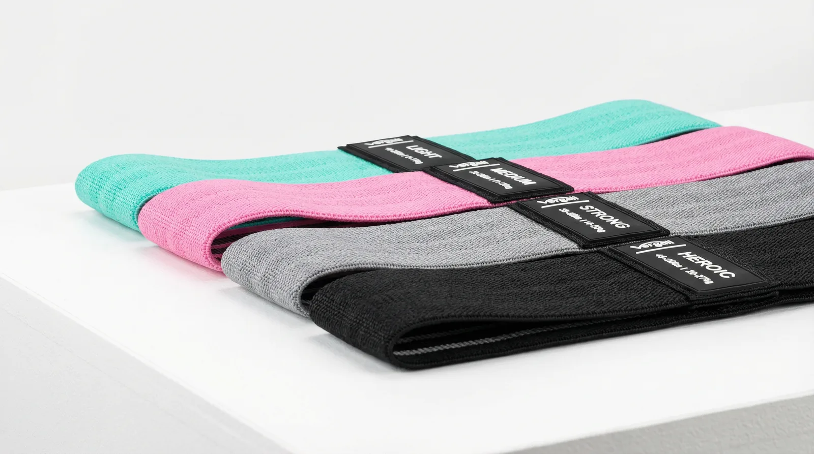 Four Vergali fabric resistance bands in aqua, pink, grey and black